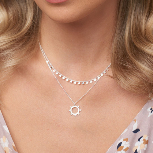 Blonde model wearing a silver necklace with many tiny silver discs. Also wearing a silver necklace with a hollow silver disc pendant.