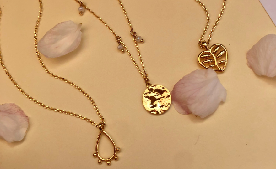 Three wavy Australian necklaces from Joya. The first gold necklace has a tear shaped gold pendant, necklace, second necklace has four pearls and a gold disc the third necklace has a gold heart pendant