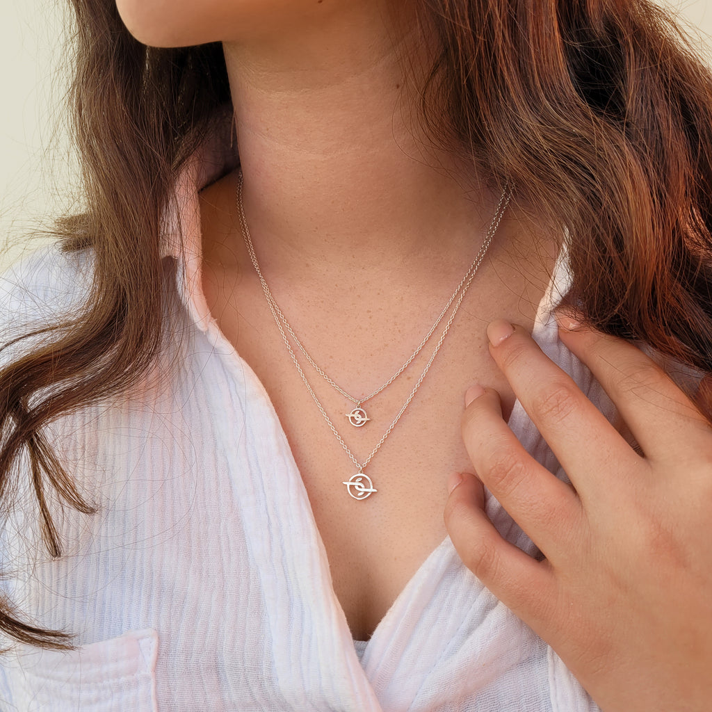 Girl with brown hair wearing two Australian solid sterling silver pendants - Joya Jewellery logo pendants on necklace