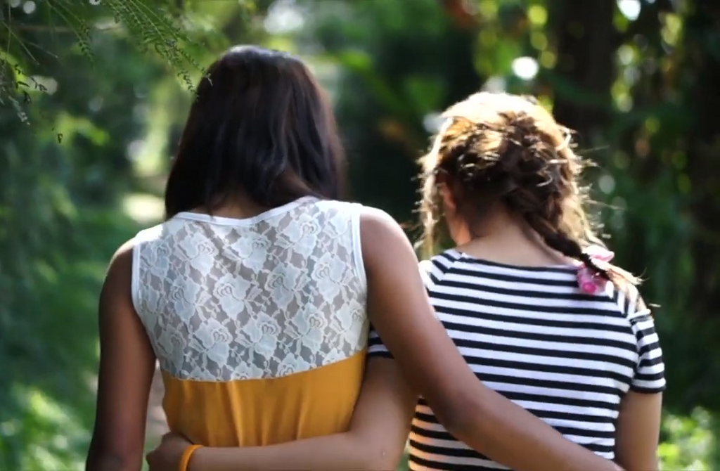 Two female survivors of human trafficking walking together down path with arms over each other
