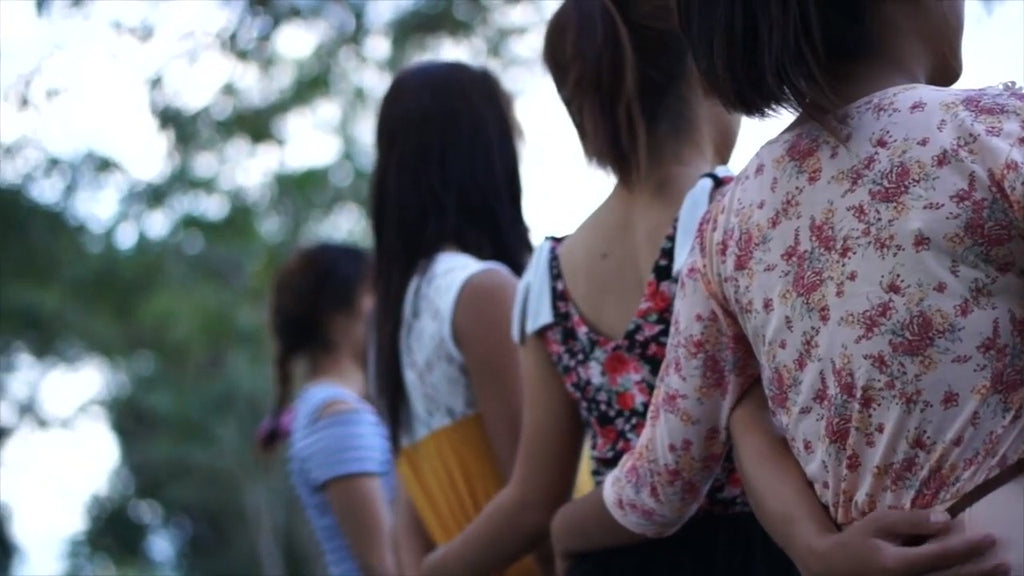 four asian girl friends facing away with arms around each other, it is assumed they are victims of human trafficking