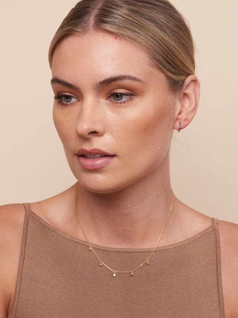 model with blonde hair displaying the starlette necklace (gold necklace with five tiny cubic zirconia's attached)