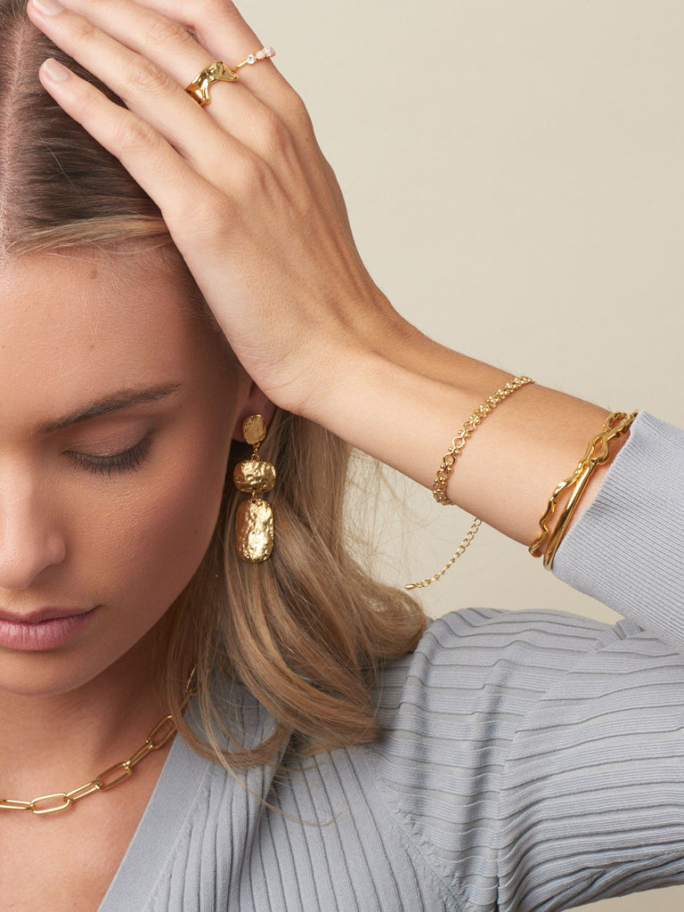 girl with brown hair and hand on head displaying australian gold earrings 