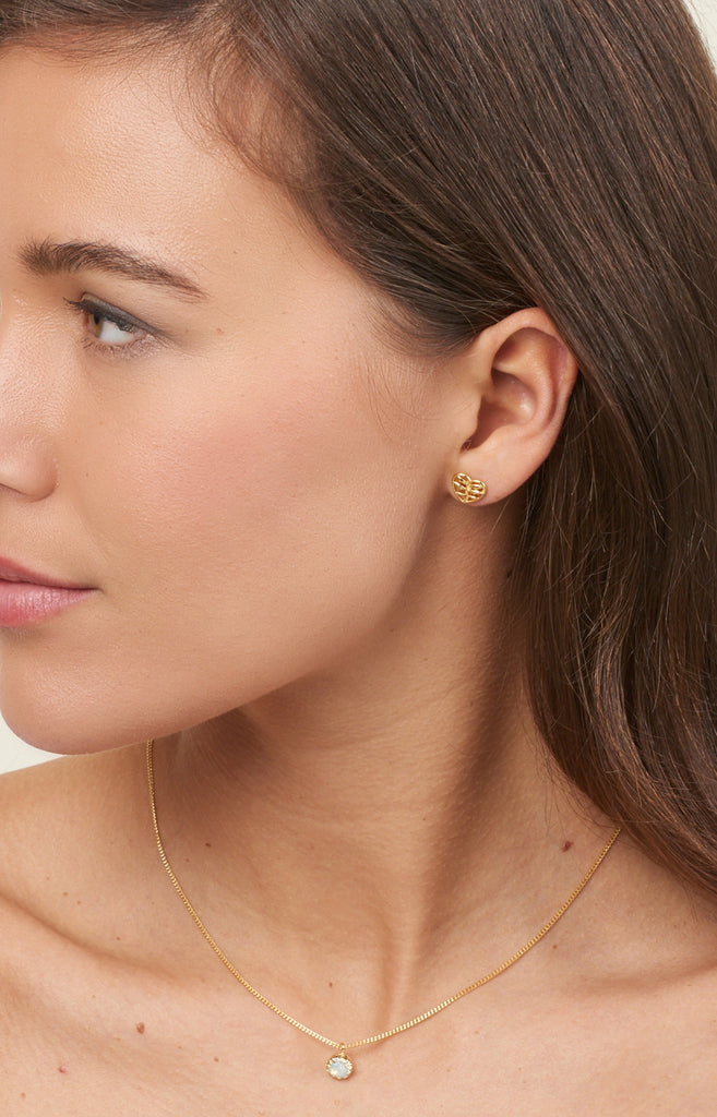 model with brown hair displaying gold earrings and gold necklace