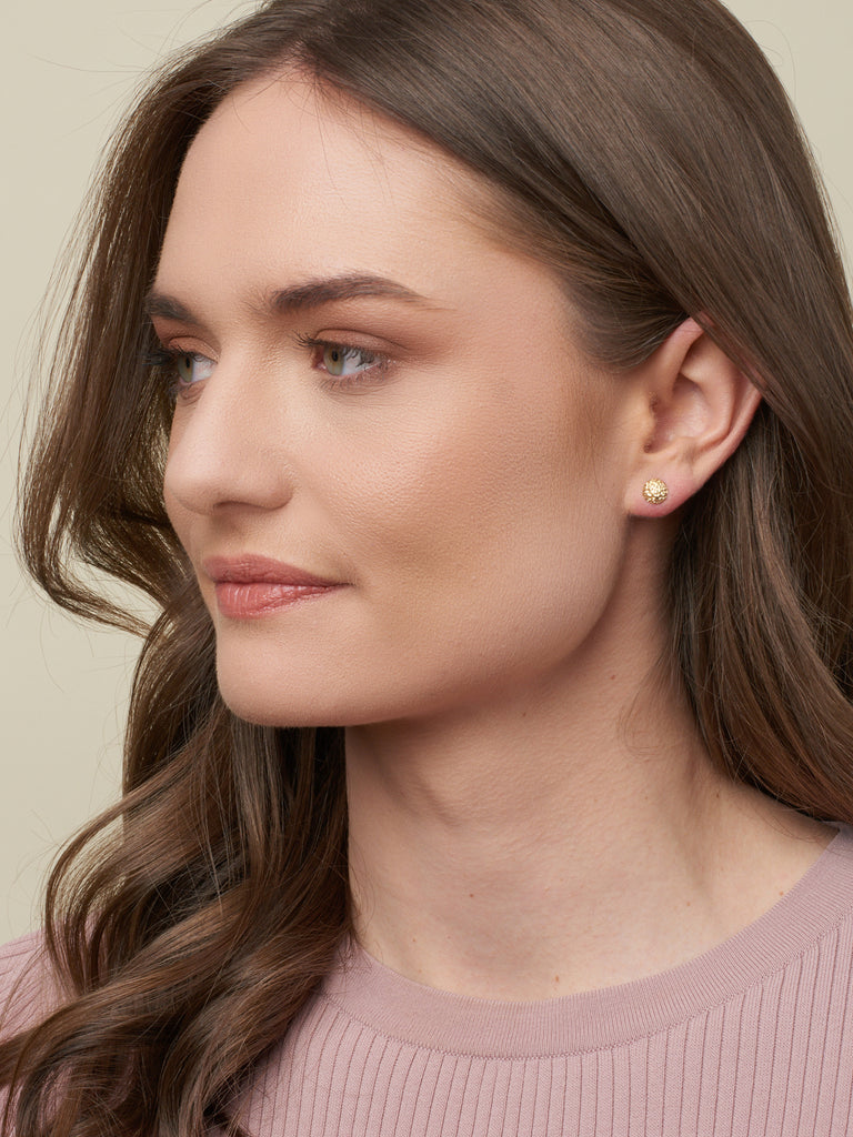 model with brown hair displaying gold earrings