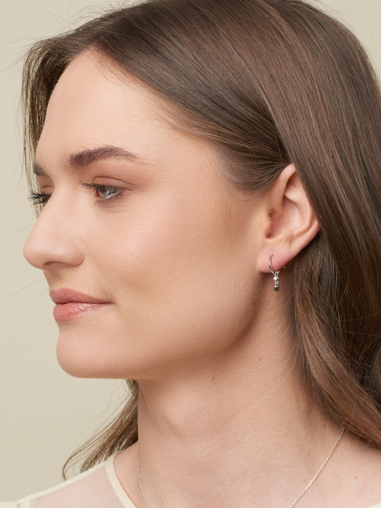 Model with brown hair wearing silver minimalist earrings with drop and cubic zirconia